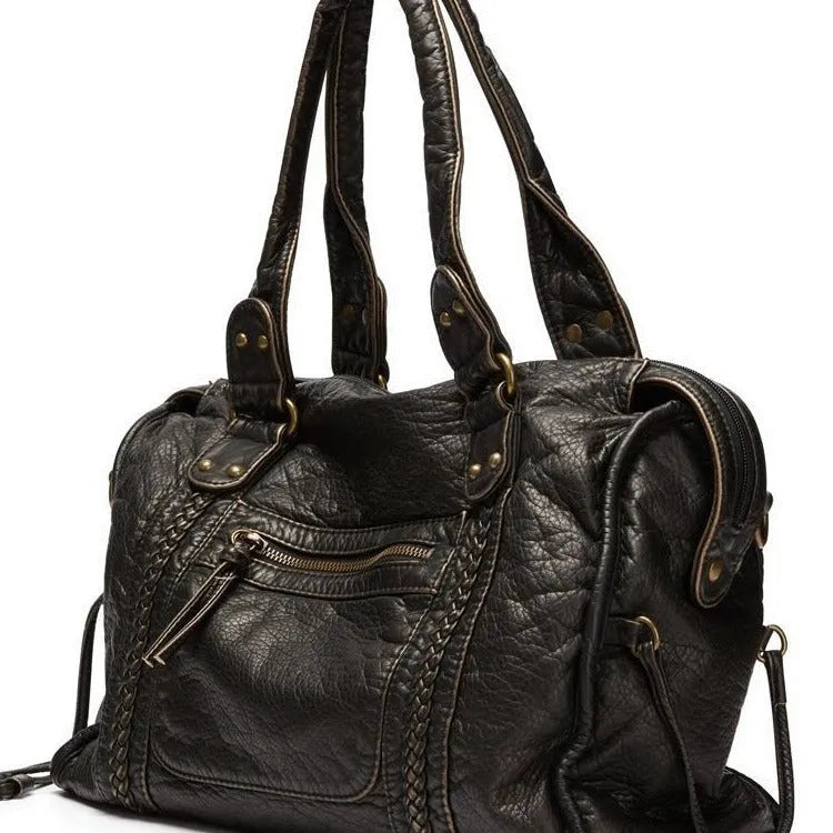Women's brown soft PU French retro motorcycle shoulder messenger bag with woven design on a table.