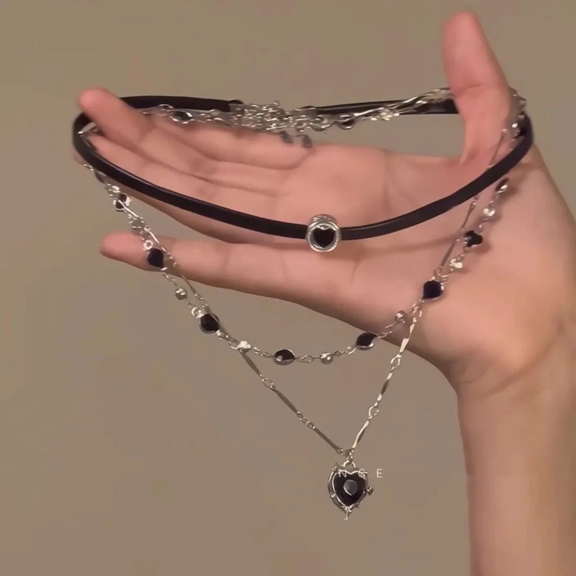Women's creative necklace set showing a double-layer leather heart necklace and a single crystal heart pendant on a metal chain.