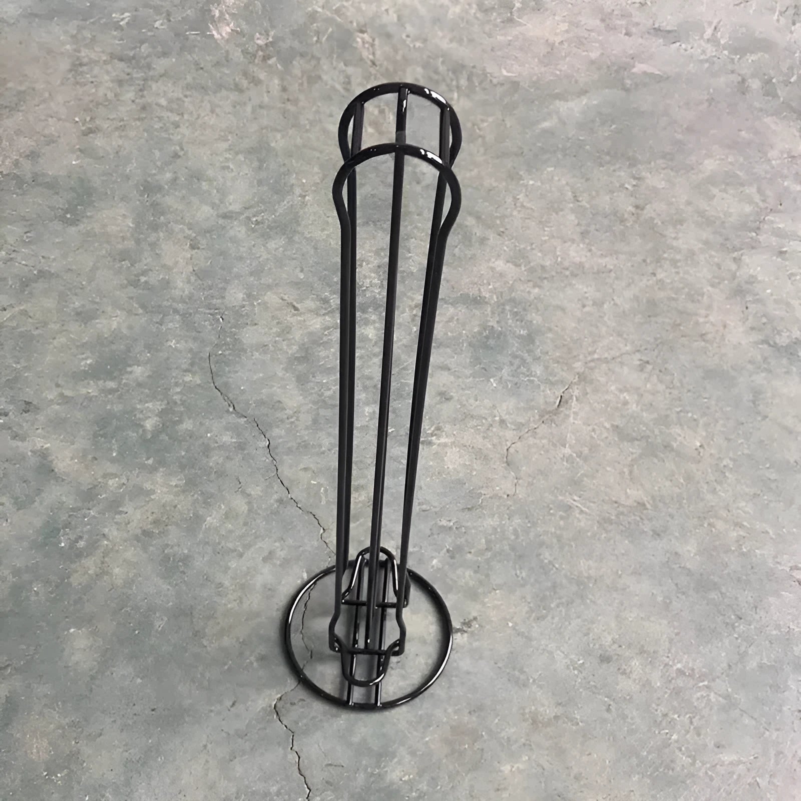 Black wrought iron coffee capsule storage rack holding twenty pods on display shelves.