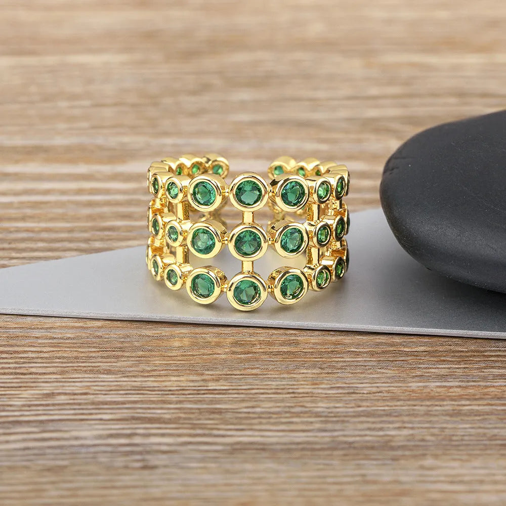 Copper and gold plated wide band ring with green zircon stones on a white background.