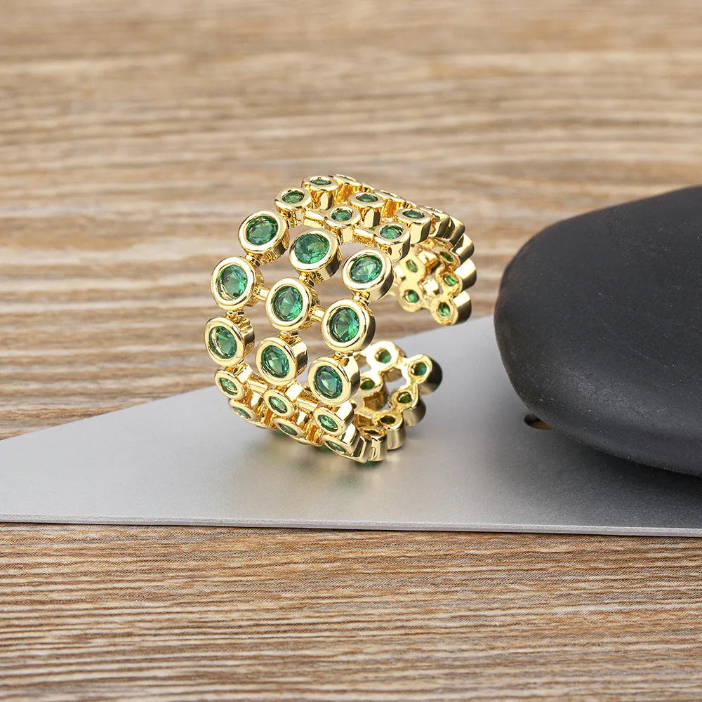 Copper and gold plated wide band ring with green zircon stones on a white background.