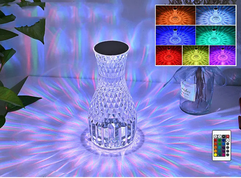 White crystal vase-shaped table lamp with remote control on a wooden surface.