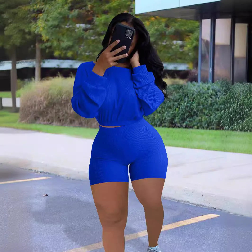 A woman wearing a solid colour off-the-shoulder long-sleeved top and matching shorts from a two-piece set.