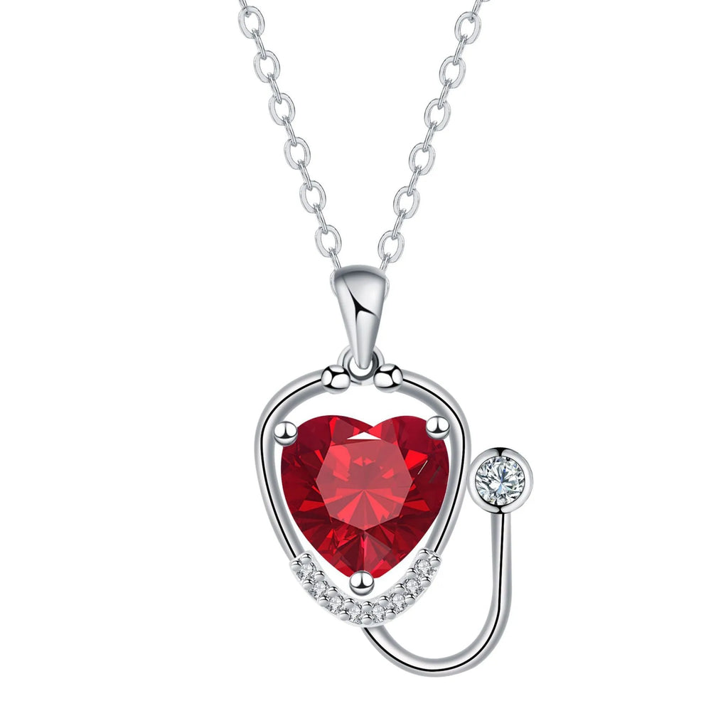 Close-up of a red diamond coloured stethoscope pendant necklace with cross, heart and wing details on a copper chain.