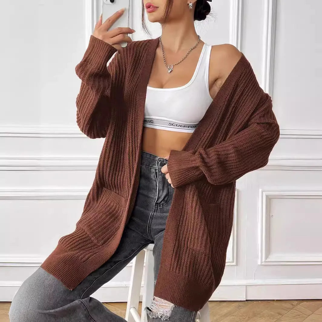 Women's dark green acrylic cardigan with two front pockets and long sleeves on a hanger.