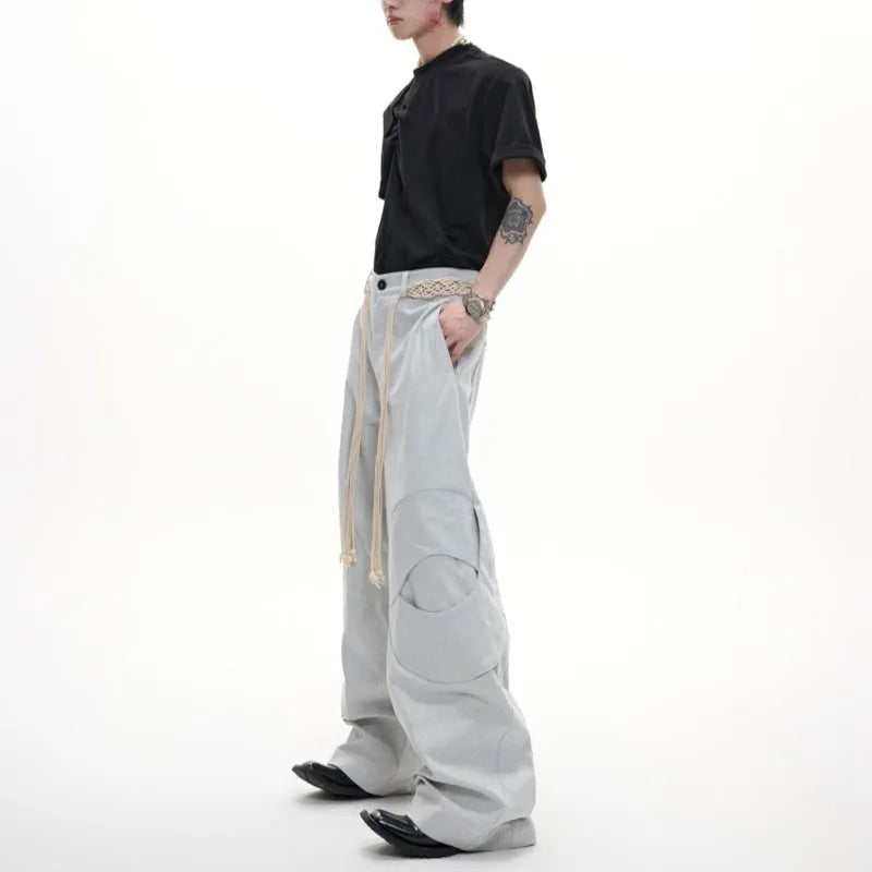 Men's dark blue loose-fit straight-leg cotton trousers with zipper decoration and tassel detail.