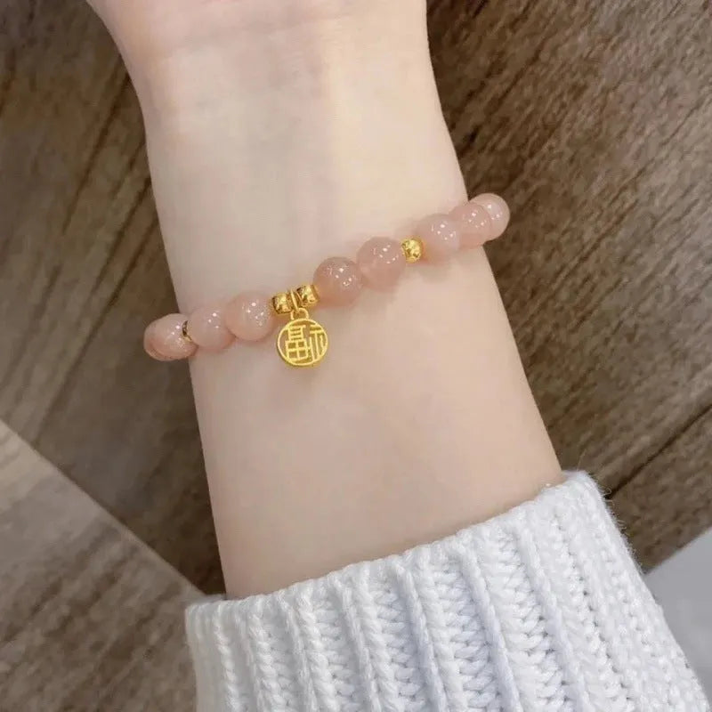 A Chinese style glass bracelet with bamboo leaf and bead designs on a wrist.