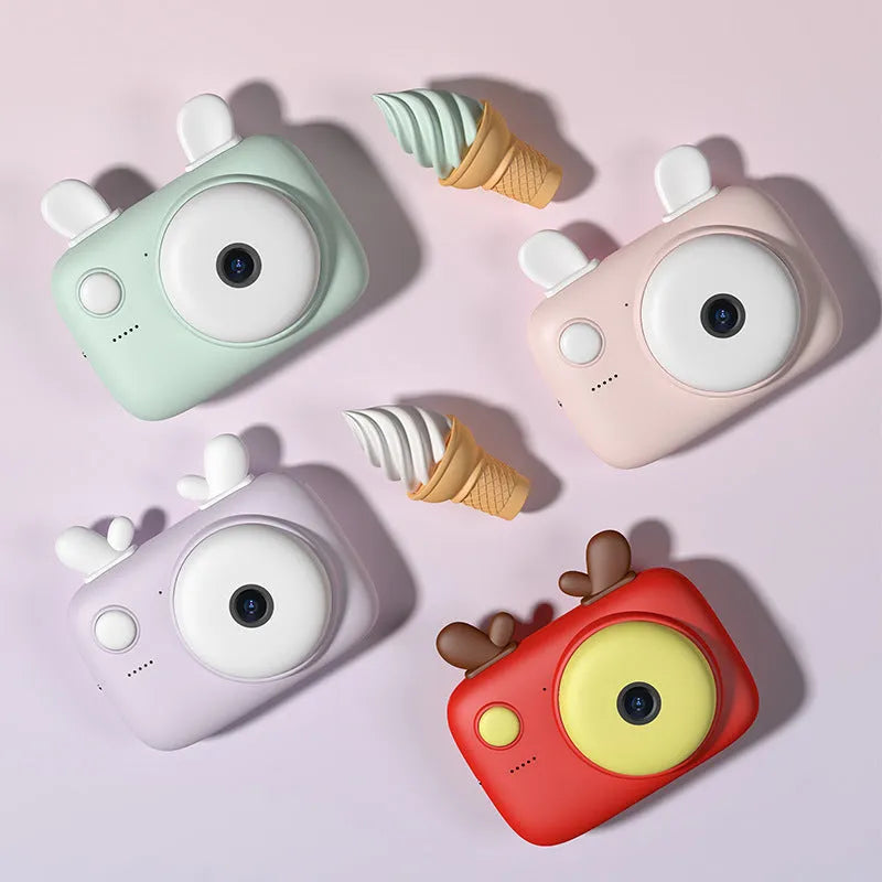 A2 Kids Macaron digital camera in green, showing front and rear lenses and 2.4-inch screen, with lanyard attached.
