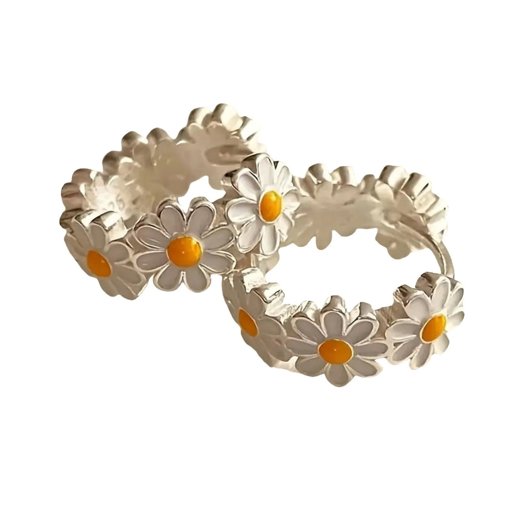 A pair of white daisy flower ring earrings with a platinum-inlaid gemstone detail.