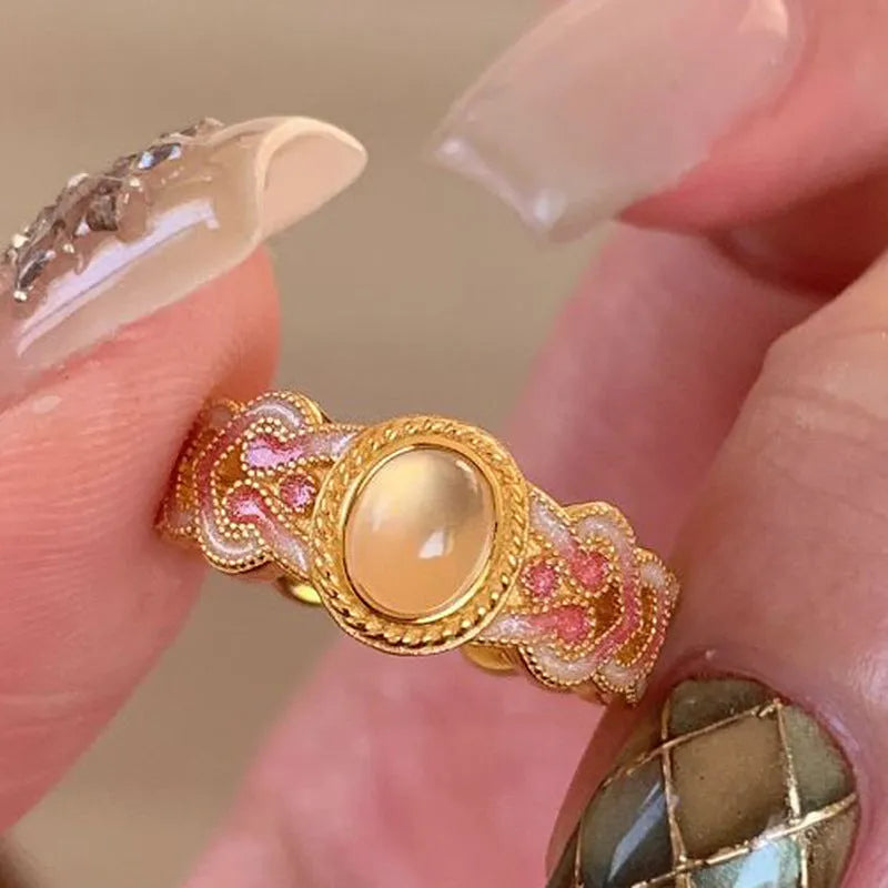Open-mouth geometric women's ring with gold plating and pink crystal enamel detail on a white background.