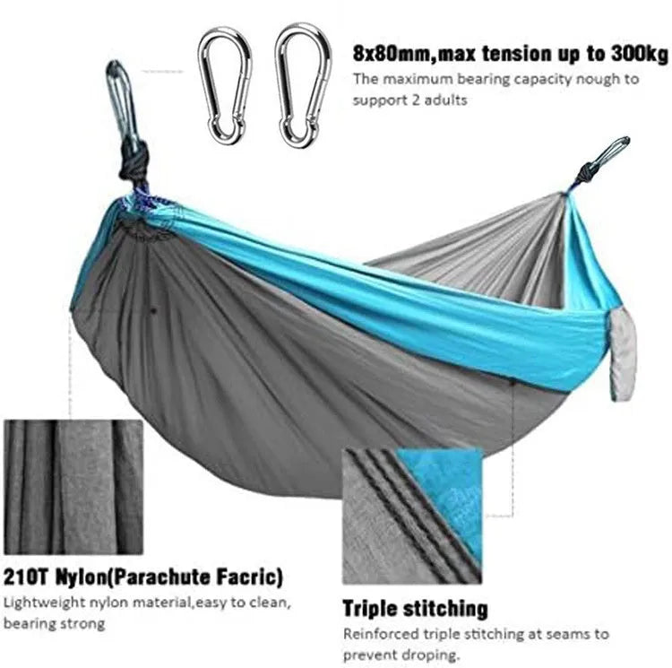 Blue nylon parachute cloth camping hammock hung between two trees outdoors.