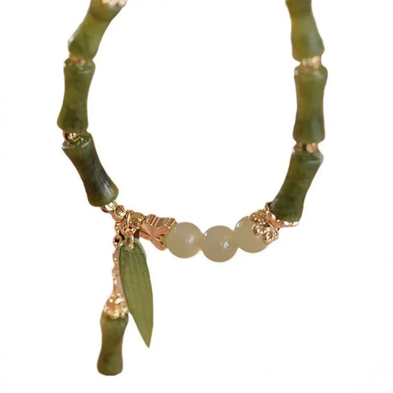 A Chinese style glass bracelet with bamboo leaf and bead designs on a wrist.
