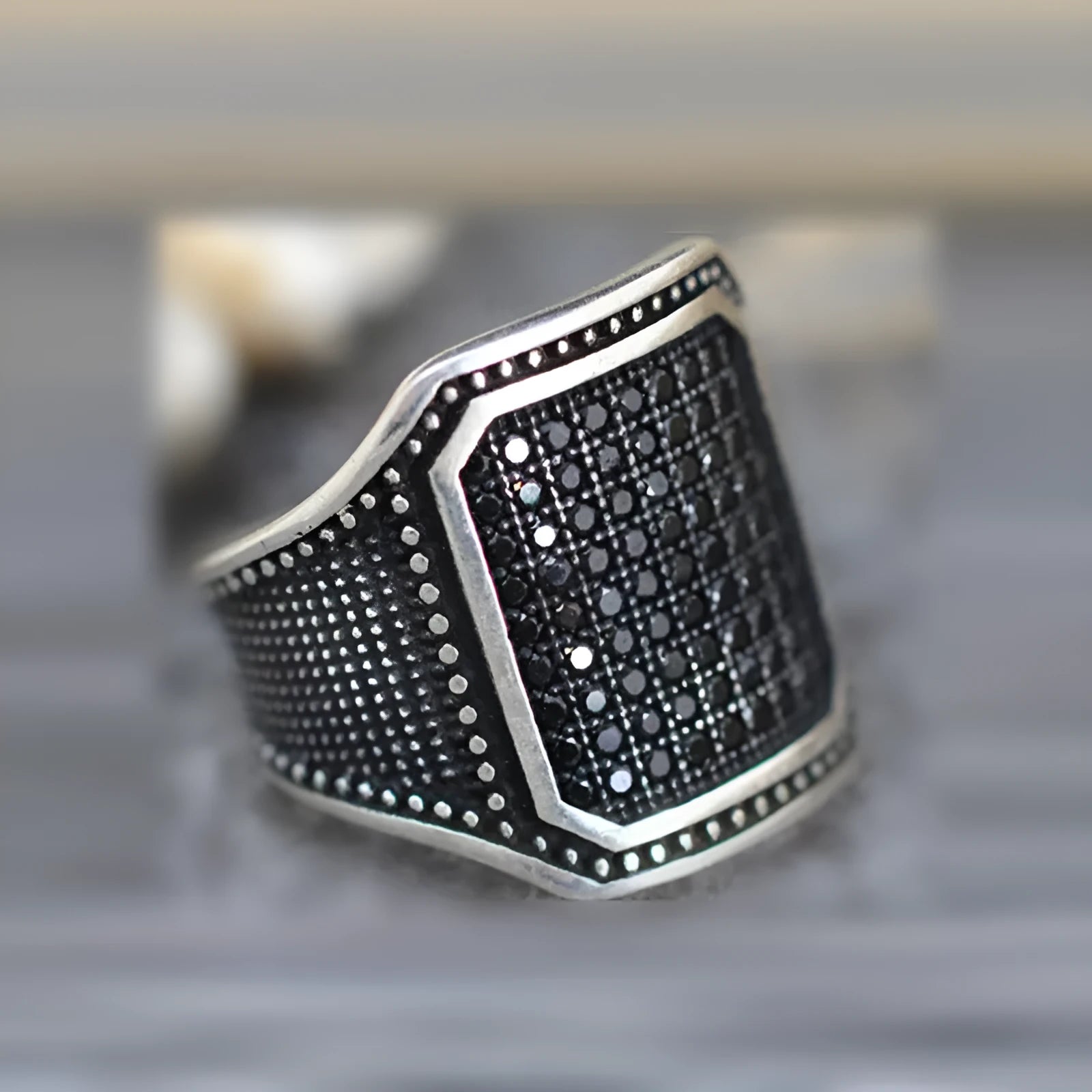 Black alloy ring with copper inlay detail and set zircon stones, shown on a hand.