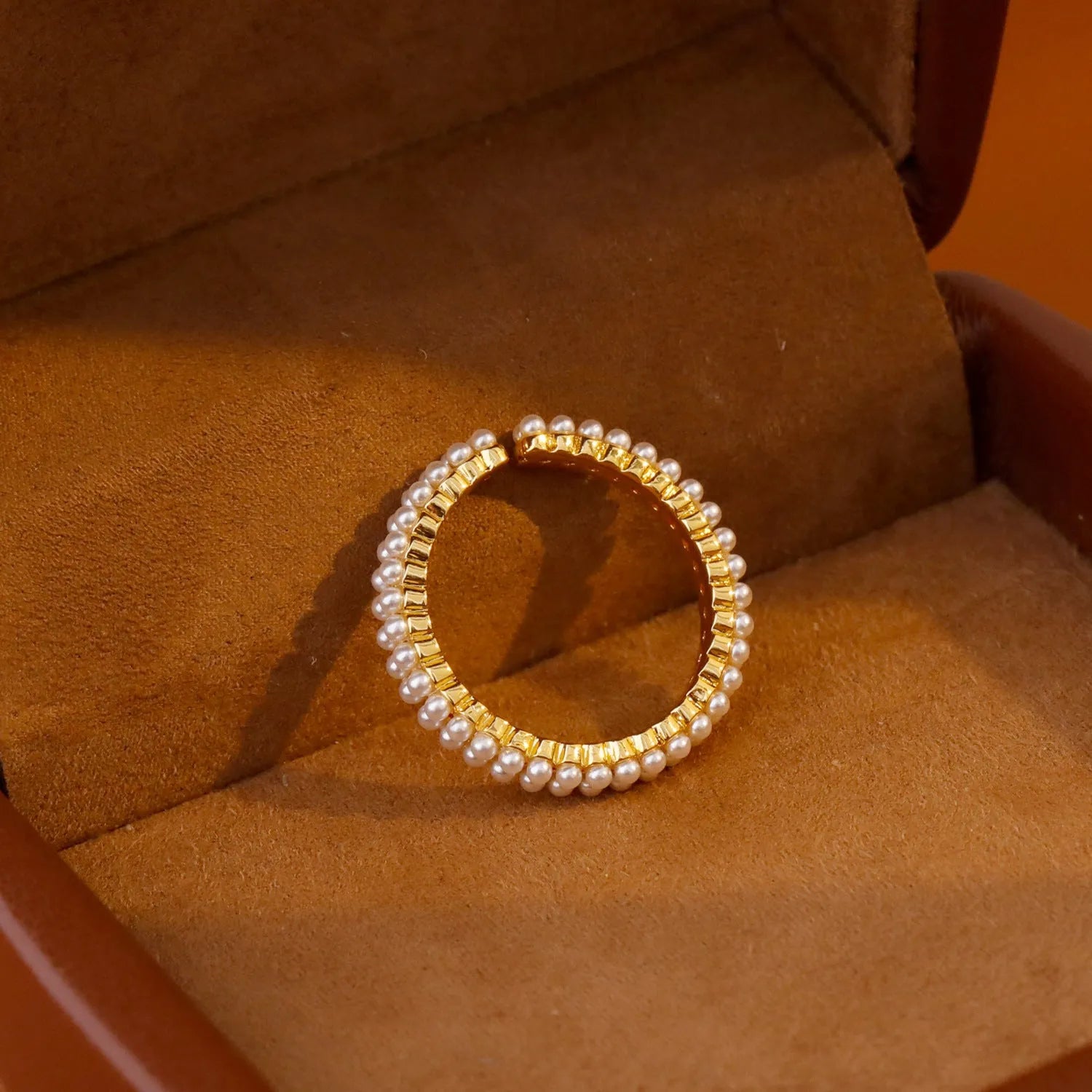 Gold coloured women's ring with open mouth design and round pearl elements on copper electroplated construction