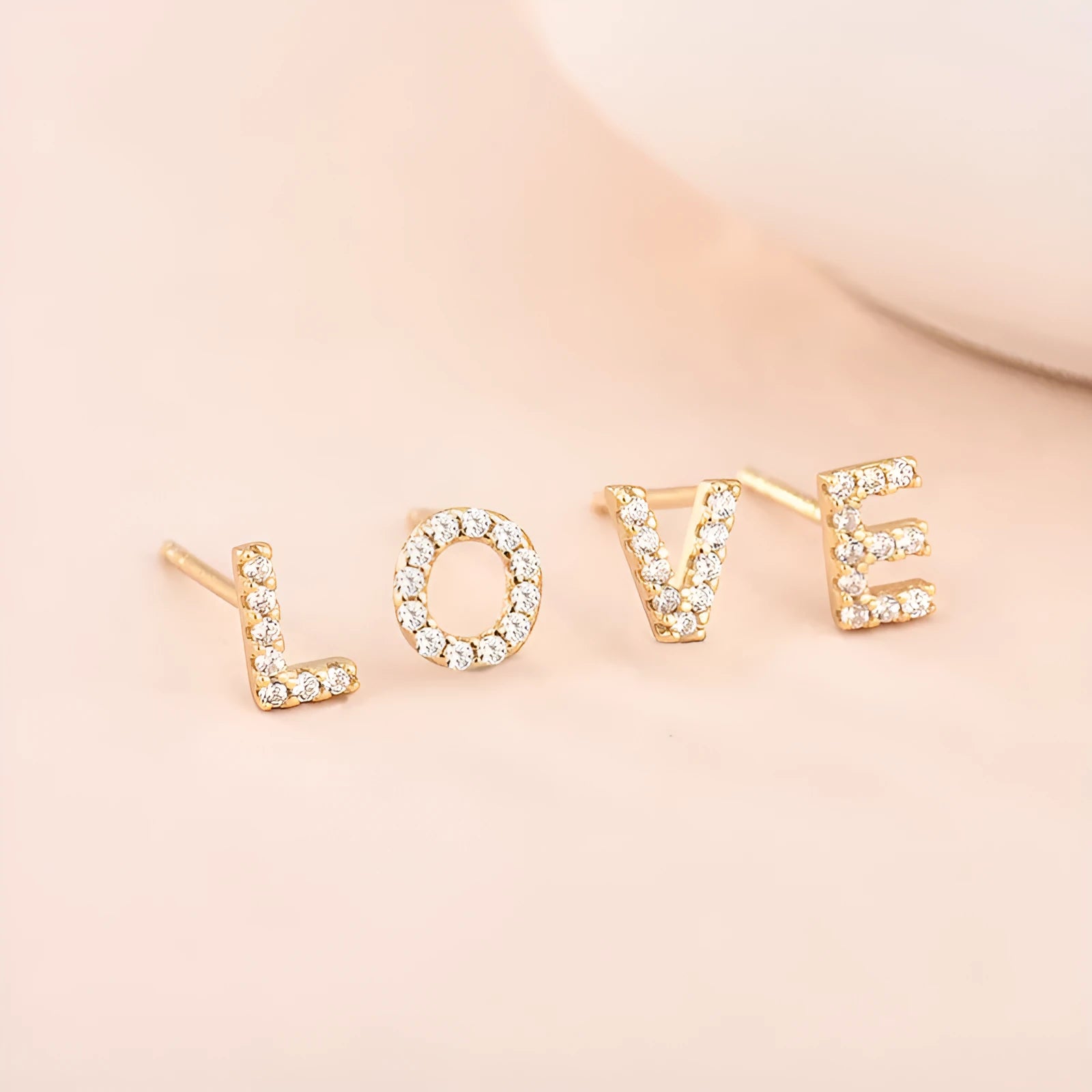 A single gold plated earring shaped like the letter A, set with small sparkling zircon stones.