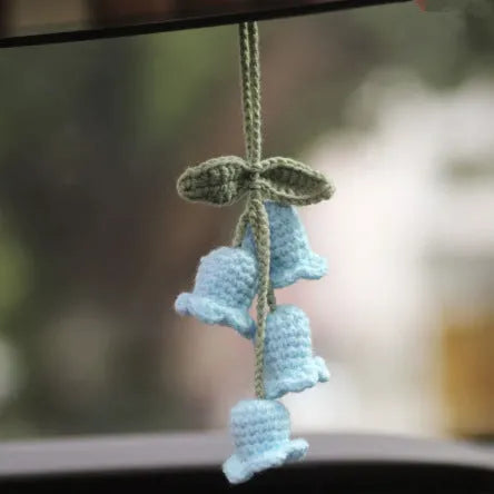 Green and white knitted car plant decoration with hanging rope on car dashboard