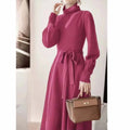 A woman wearing a rose red knitted turtleneck sweater dress with long sleeves, an elastic waist, and a loose, big hem.