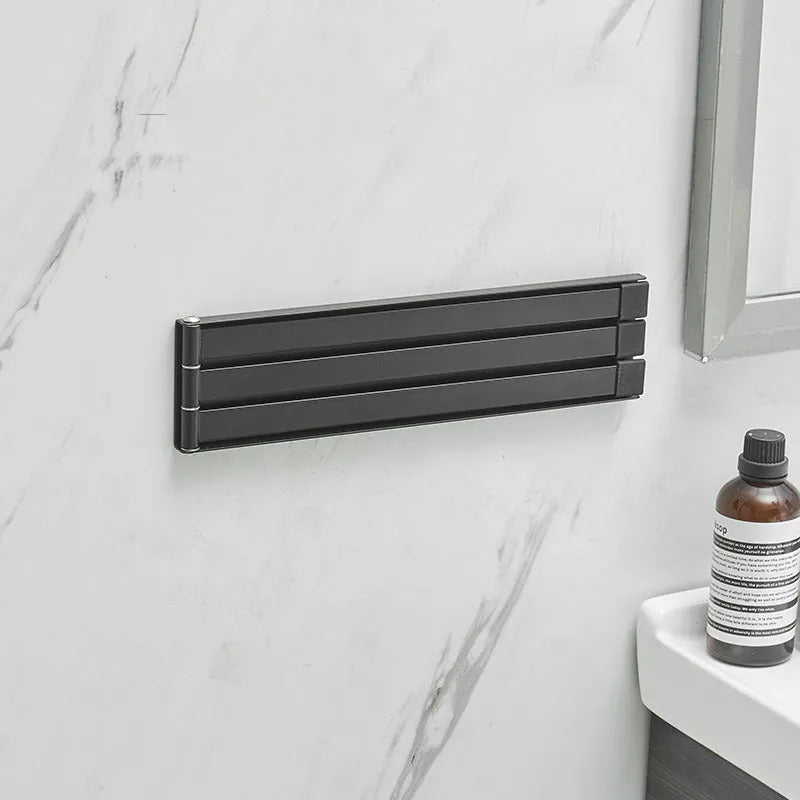 Nordic style black folding towel rack mounted on a white bathroom tile wall.
