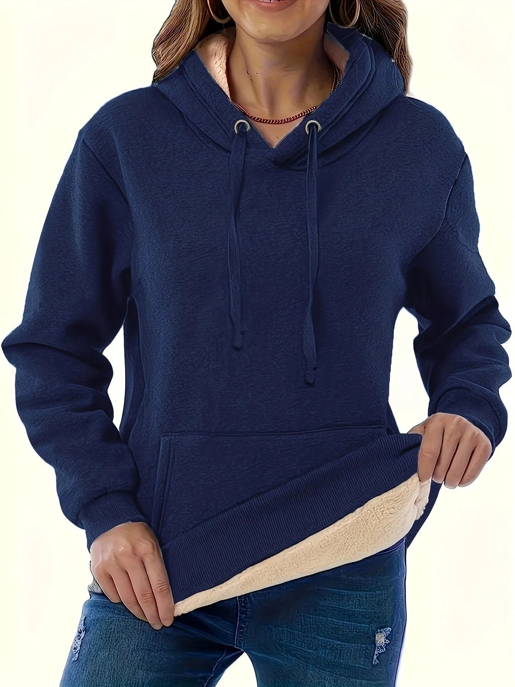 Woman wearing a thick, grey hooded sweater with a raised 3D pattern, featuring long sleeves and pockets.