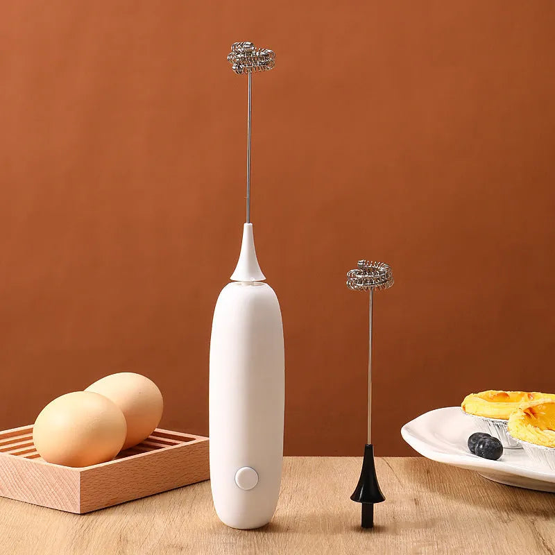 Black and white handheld electric milk frother with whisk attachment for coffee drinks