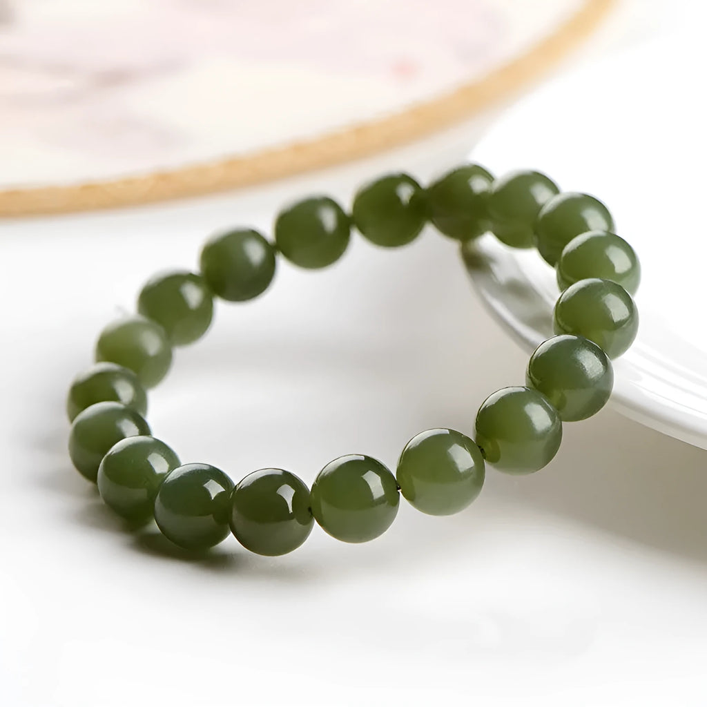 Hetian jade ball bracelet on wrist showing polished spherical beads on an elasticated string in a clear colour.
