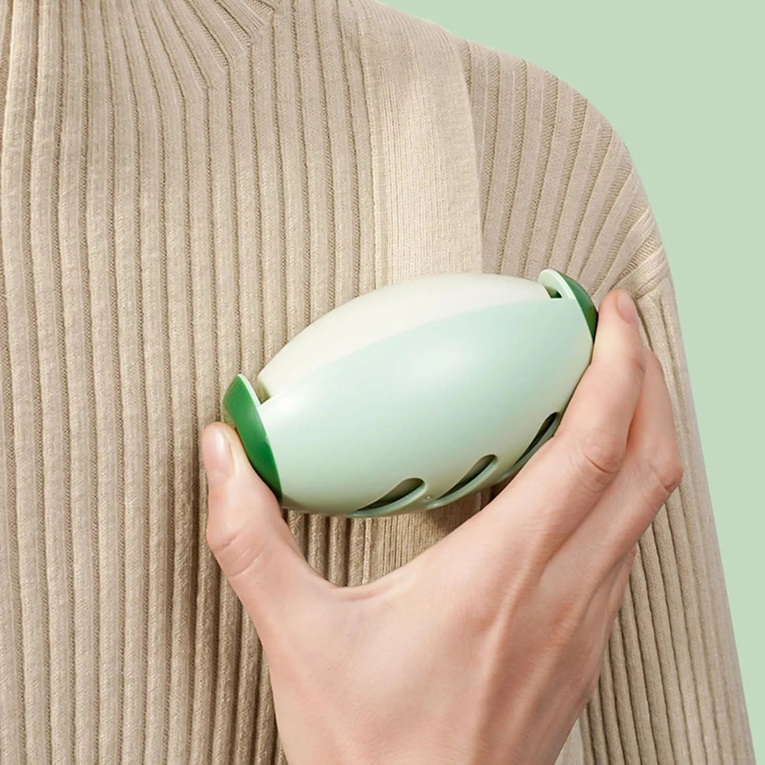 Green and white reusable gel lint roller ball for pet hair removal on fabric.