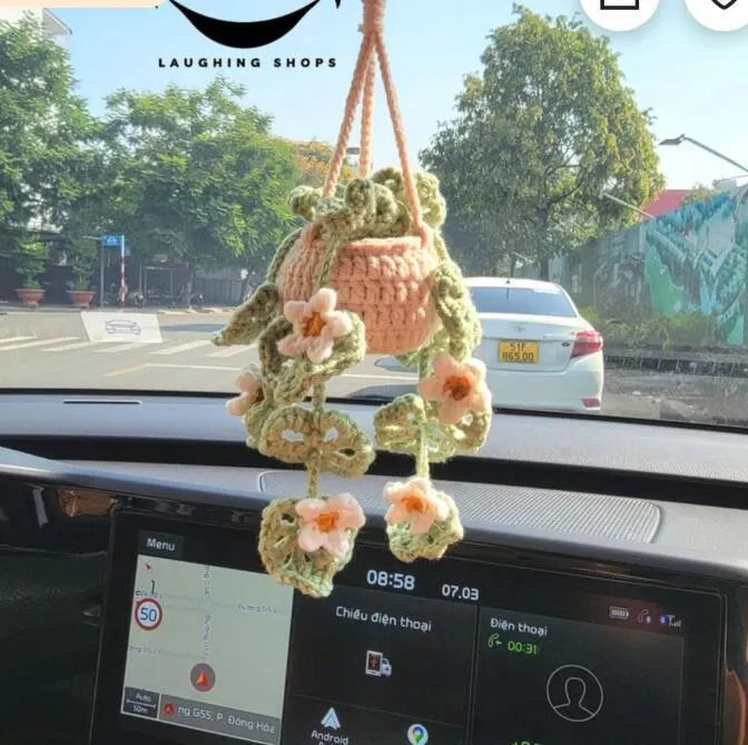 Green and white knitted car plant decoration with hanging rope on car dashboard