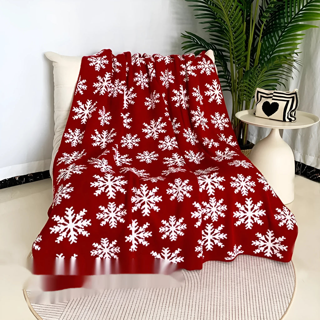 Personalised Christmas blanket with snowflake or reindeer design on a sofa.