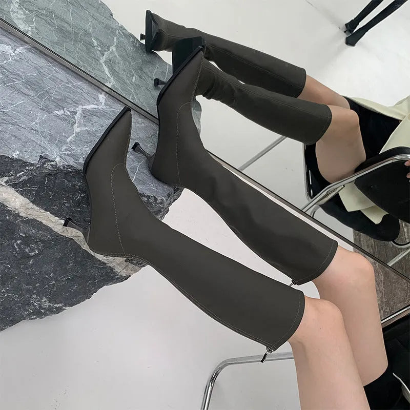 Black women's pointed toe below-the-knee boots with a stiletto heel and a back zipper closure on the side.