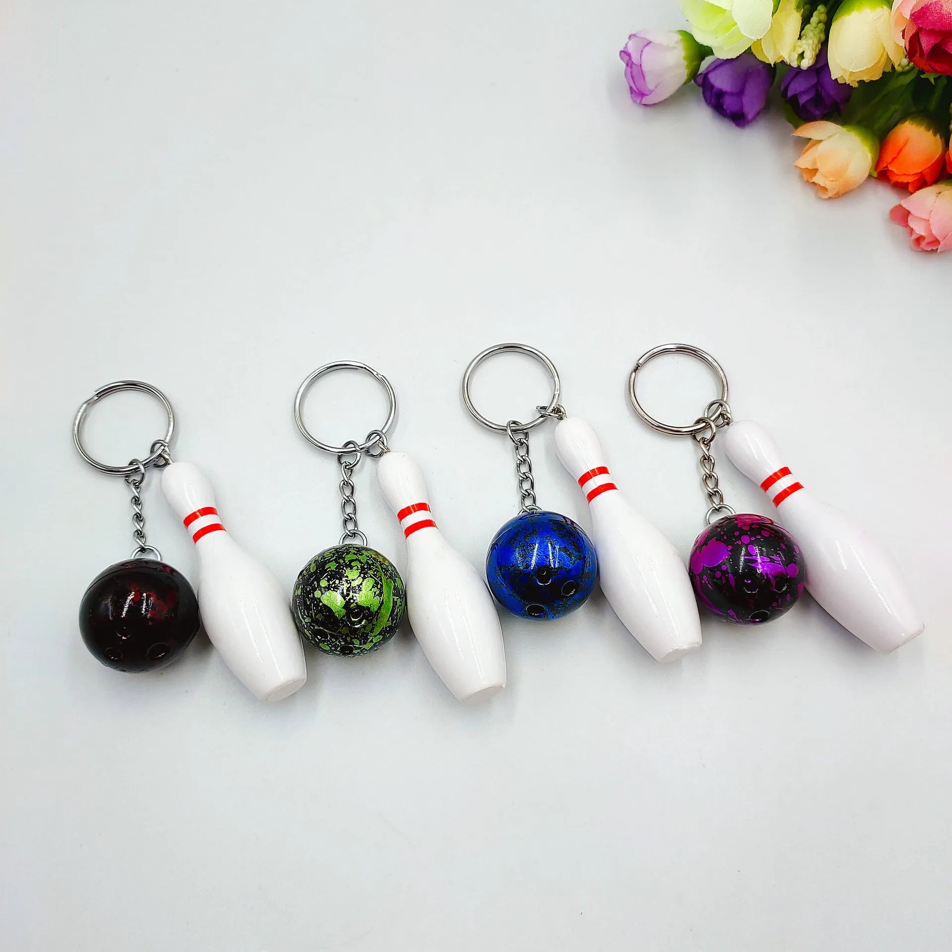 Miniature blue bowling ball keychain pendant with metal keyring on a dark surface.