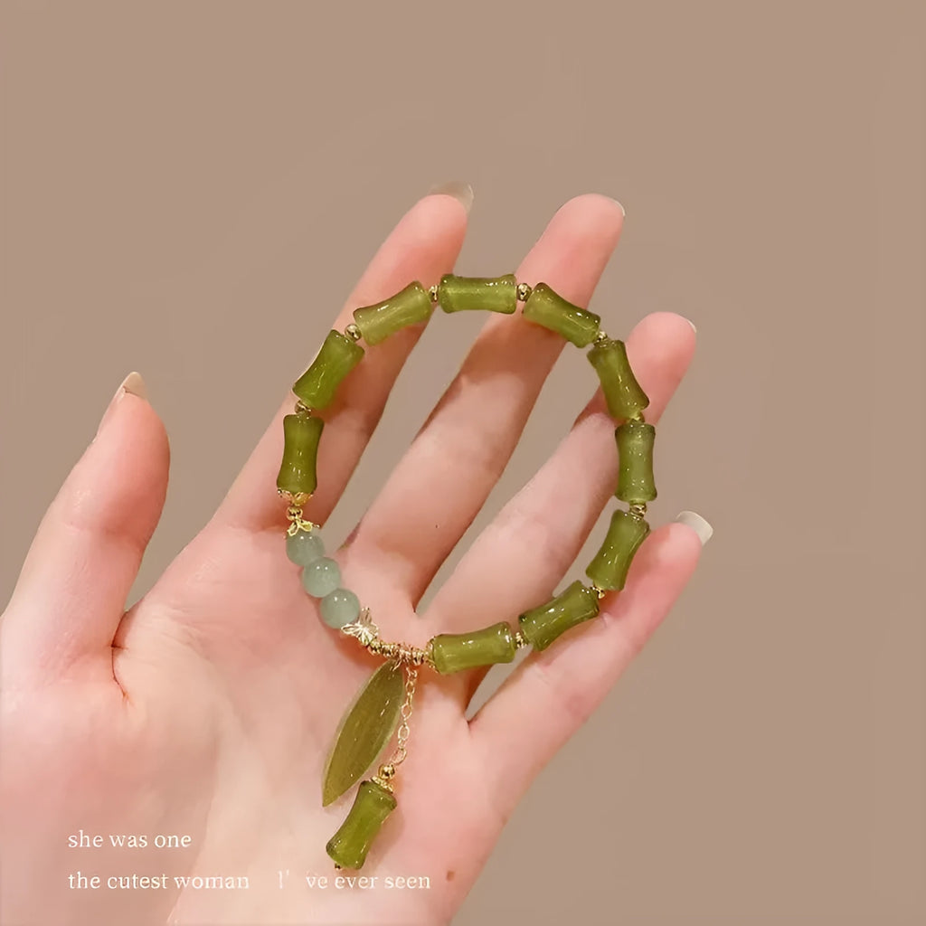 A Chinese style glass bracelet with bamboo leaf and bead designs on a wrist.