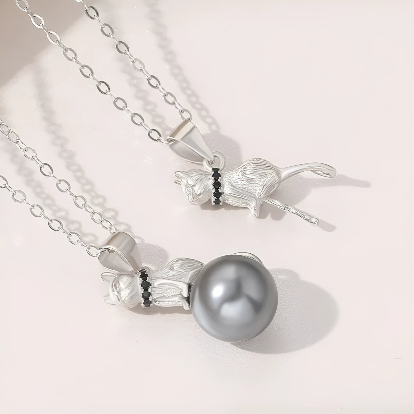 Close-up of a sterling silver cat pendant on a clavicle chain, showing detailed feline design and bright electroplated finish.