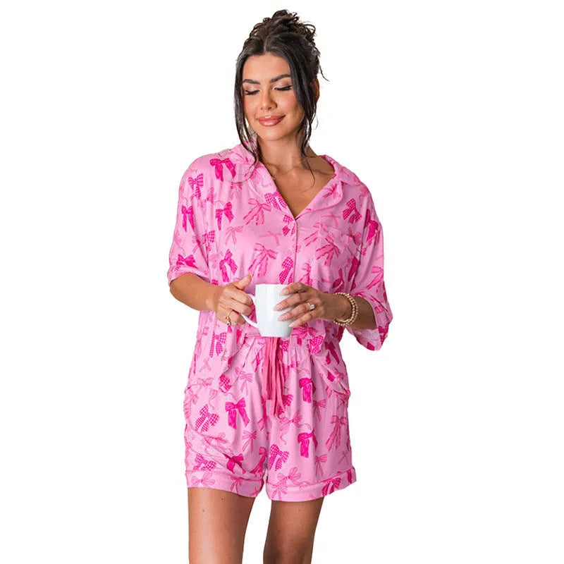 Pink two-piece polyester pajama set with a bow print, shown as a top and pants for sleepwear