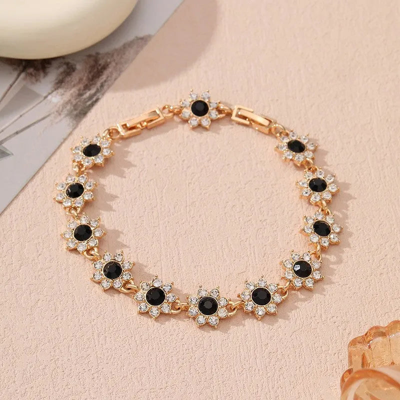 Gold tone flower-shaped bracelet with blue crystal gems on a wrist.