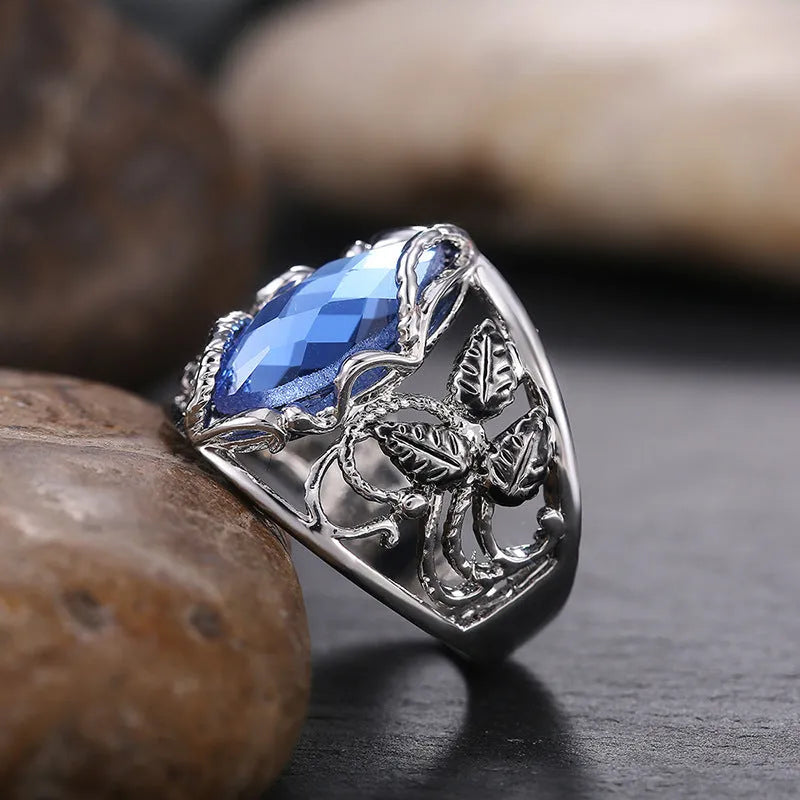 Women's horse eye shaped blue crystal alloy ring on a finger, showing geometric design.