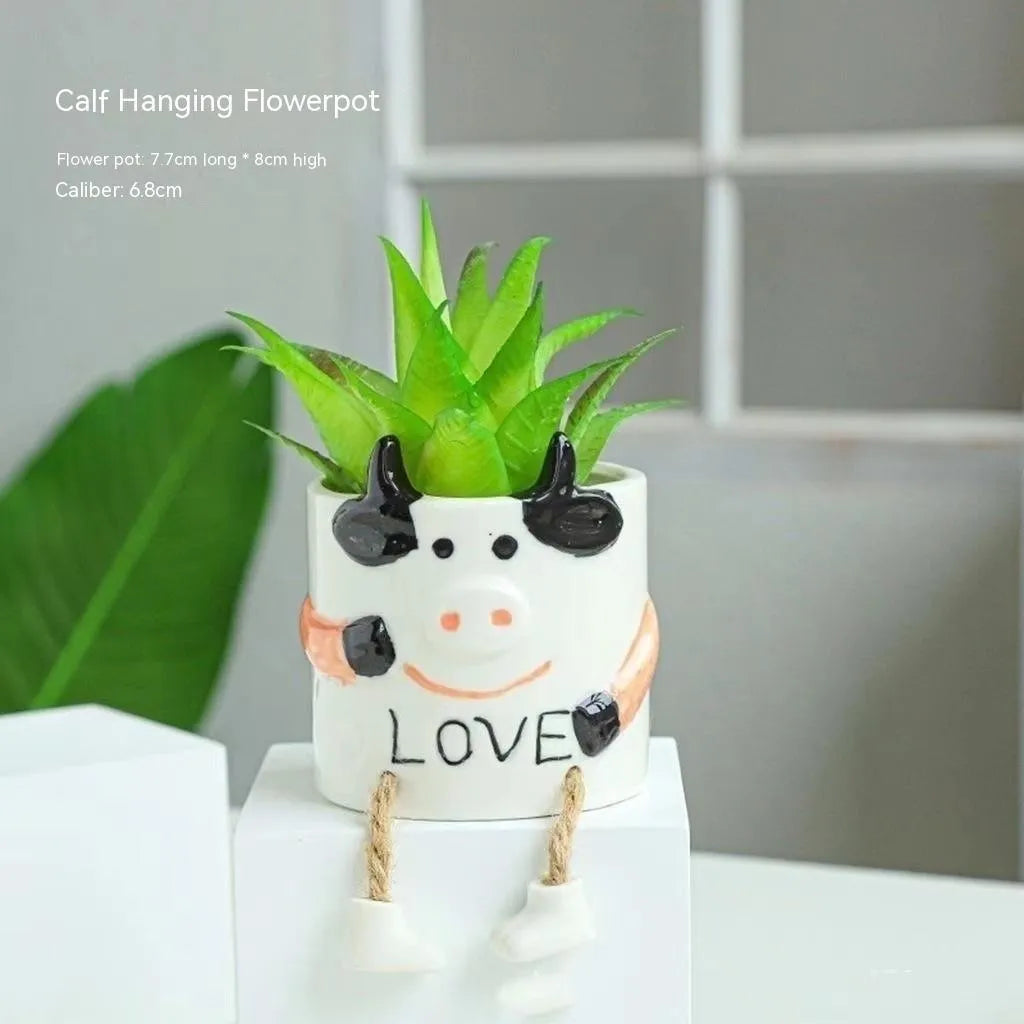 Ceramic cartoon-style succulent flowerpot with hanging foot design on desktop
