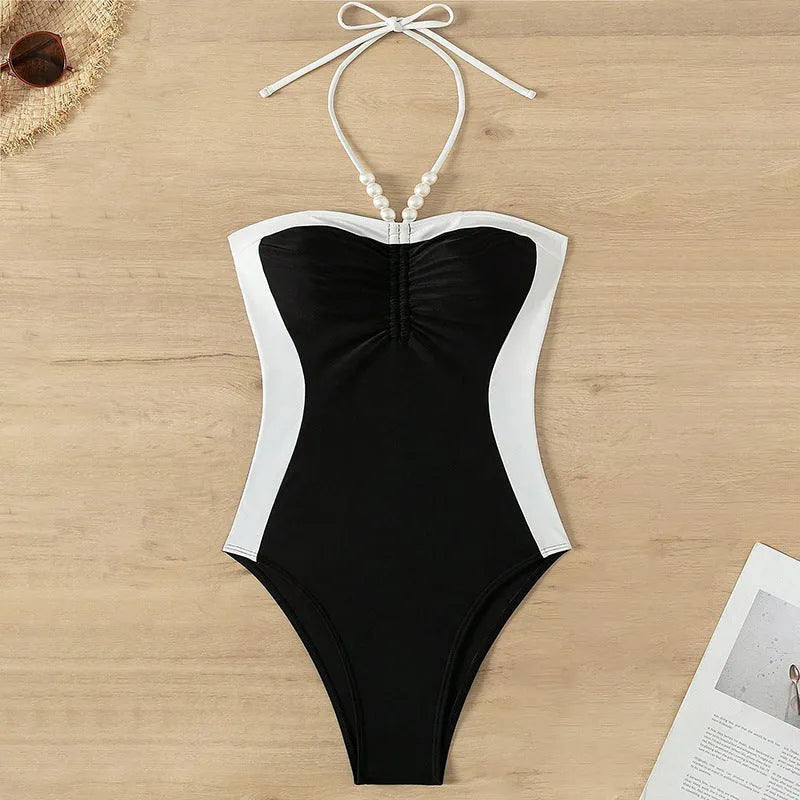 Black and white women's one-piece swimsuit with pearl spaghetti straps and a slimming cut.