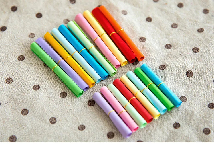 Assorted colourful mini paper scrolls with central metal eyelets for drift bottle messages.