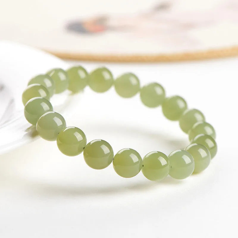 Hetian jade ball bracelet on wrist showing polished spherical beads on an elasticated string in a clear colour.