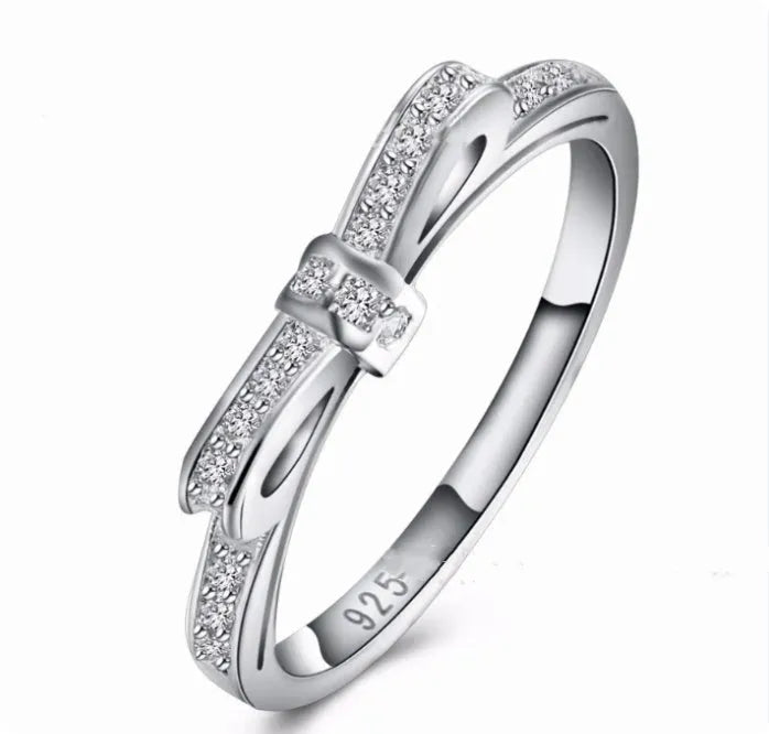 Silver bow ring with zircon crystal and rhinestone detailing on finger