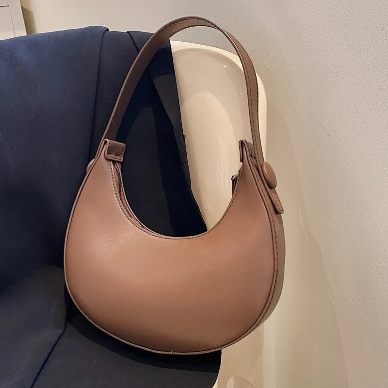 Women's retro-style dumpling-shaped PU leather shoulder bag in cream yellow, showing sandwich pocket.