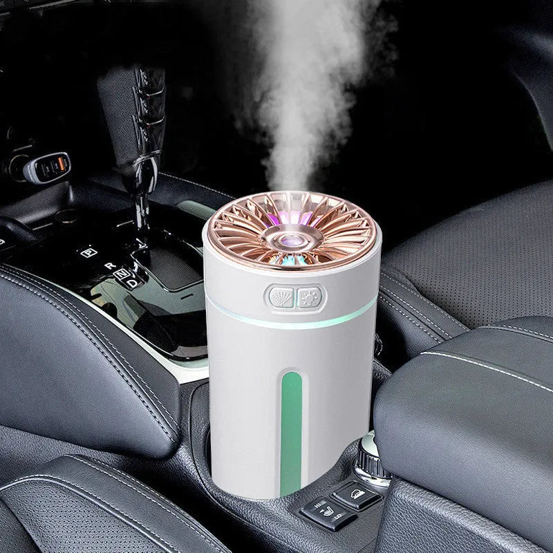 Black portable USB rechargeable car humidifier with colourful lights on a desk next to a cup