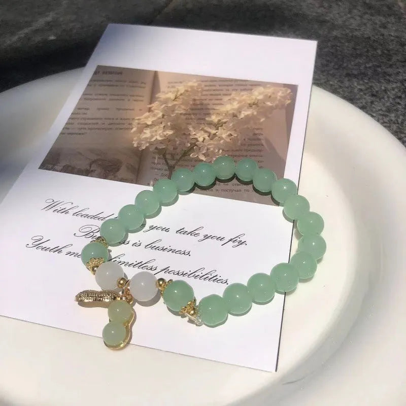 A Chinese style glass bracelet with bamboo leaf and bead designs on a wrist.