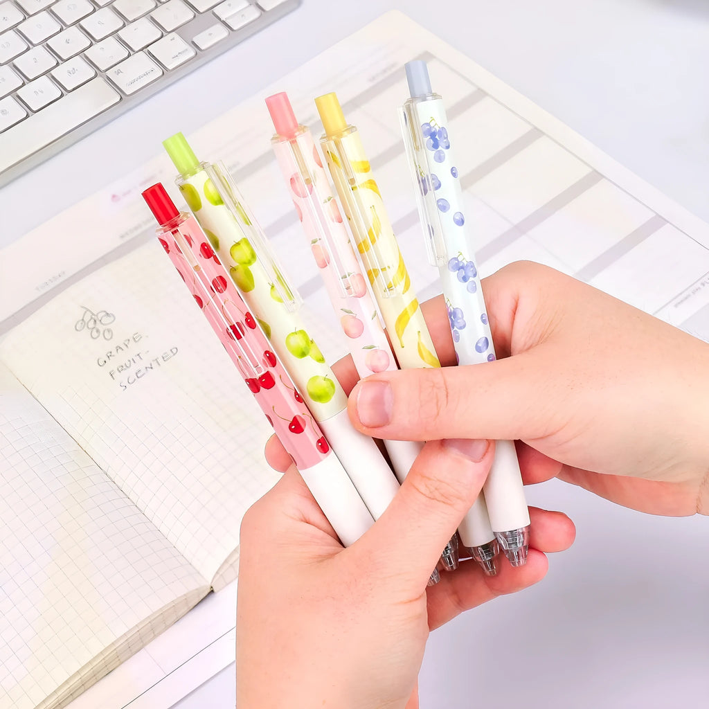 Three fruit-themed scented pressurised pens with 0.5mm black ink refills on writing surface