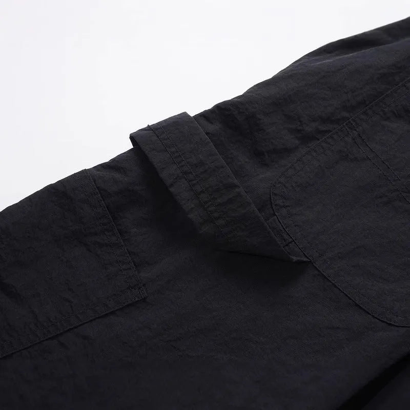 Black paratrooper trousers with elastic waist and drawstring closure, showing baggy fit and three-dimensional cutting