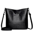 Women's solid colour soft leather bucket shoulder bag with sewing detail on strap, shown in ginger yellow.