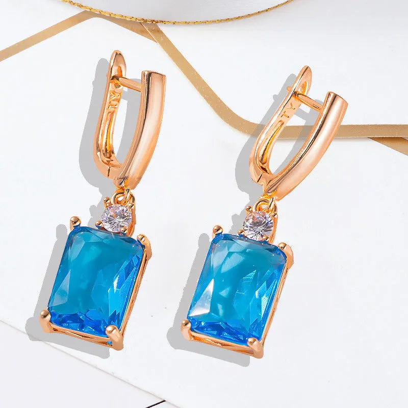 A pair of square geometric earrings with an electroplated gold finish on a copper base.