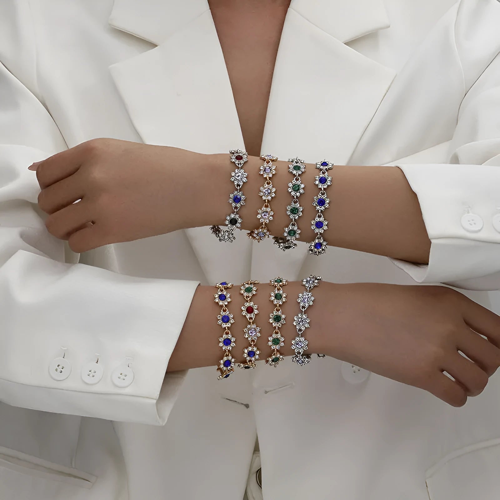 Gold tone flower-shaped bracelet with blue crystal gems on a wrist.