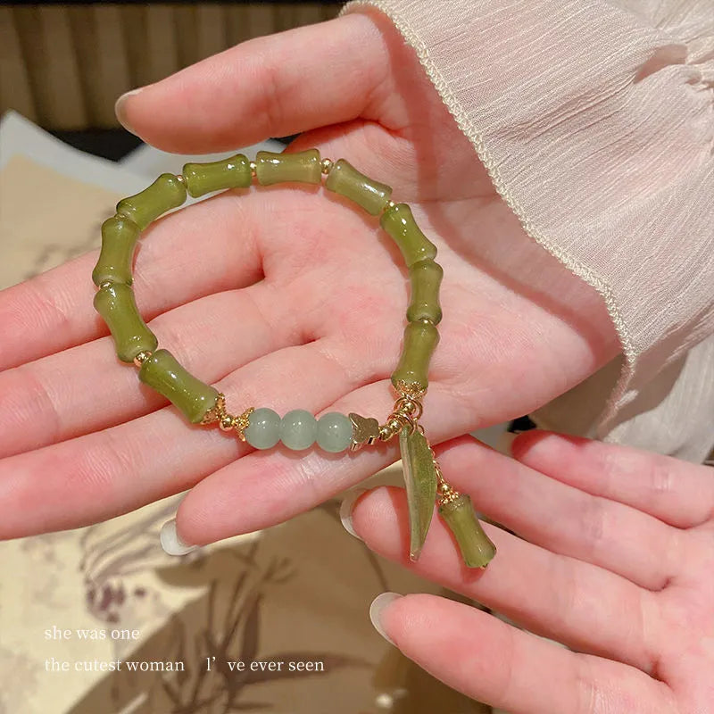 A Chinese style glass bracelet with bamboo leaf and bead designs on a wrist.