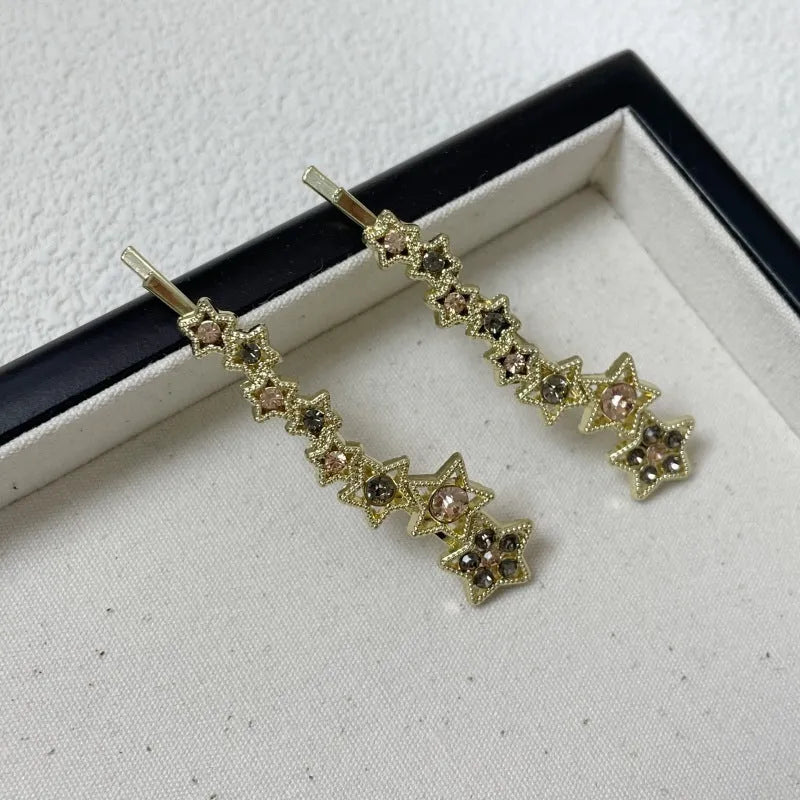 Gold-coloured alloy hair barrette with rhinestone star charm, shown clipped to hair.